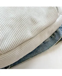 Close-up of cream corduroy crossbody bag texture and matching white zipper detail