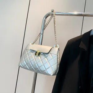 Sac bandoulière argenté matelassé avec chaîne dorée et fermoir rotatif sur support