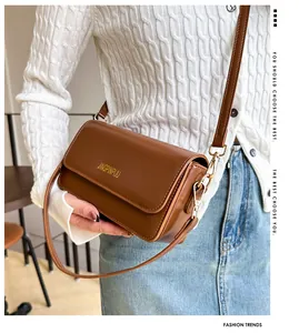 Detail of brown smooth leather crossbody bag with gold text on the front flap