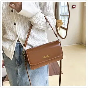Close-up of brown PU leather shoulder bag with gold branding and magnetic flap closure