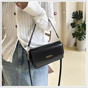 Detail of a chic black flap crossbody bag with gold logo and adjustable shoulder strap
