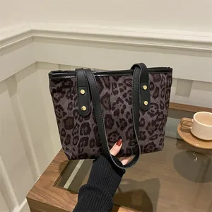 Detail of large leopard print tote bag with black leather straps and gold metal rivets