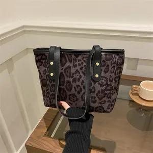 Detail of leopard print tote bag with black leather straps and gold metal rivets
