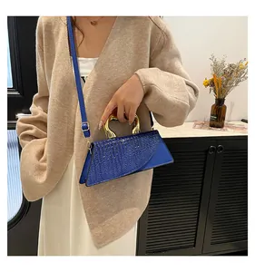 Blue crocodile pattern handbag with gold handle and shoulder strap in lifestyle view