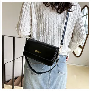 Detail of a black retro baguette bag with dual leather straps and gold metal hardware