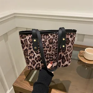 Close-up of leopard print tote bag with black straps and golden rivet details