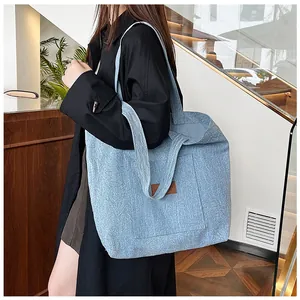 Détail du grand sac cabas en denim bleu clair avec texture et étiquette en cuir marron