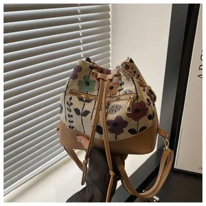 Detail of vintage floral canvas bucket bag with brown leather trim and front zip pocket