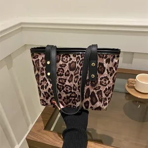 Detail of leopard print tote bag with black leather straps and golden rivets on canvas