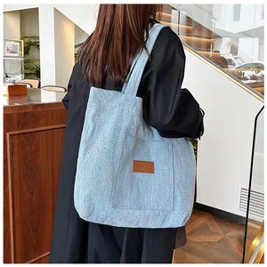 Détail du grand sac cabas en denim bleu clair avec texture et écusson en cuir marron