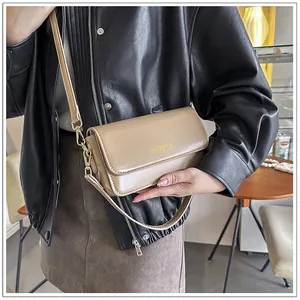 Detail shot of a beige minimalist crossbody bag with gold hardware and fine matte texture