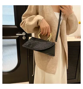 Detail of black crocodile texture handbag with unique golden metal handle and shoulder strap