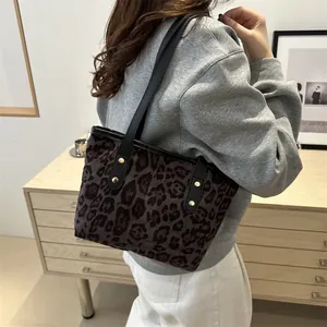 Close-up of leopard print tote bag featuring black leather straps and gold metal rivets