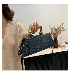 Detail of navy croc-embossed leather handbag featuring a polished gold round metal handle