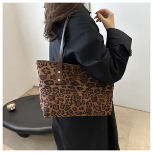Close-up of leopard print tote bag with brown leather handles and metal brand logo