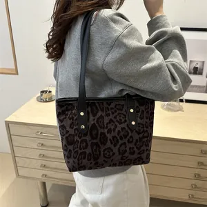 Close-up of leopard print tote bag with black leather straps and metal rivet details