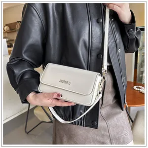 Detailed close-up of a white leather flap square bag with embossed logo and golden buckle