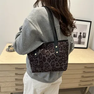 Close-up of leopard print tote bag with black straps and golden metal rivets detail