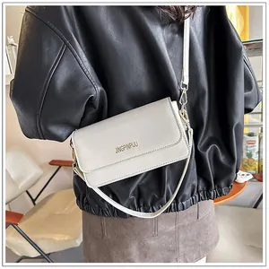 Detailed back view of model wearing a stylish off-white leather shoulder bag with gold logo