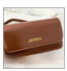 Close-up of brown matte leather handbag with golden logo and neat stitching details