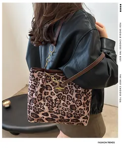 Detail shot of leopard print tote bag with brown leather handles and metal chain accents