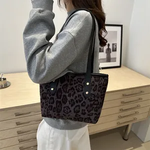 Detailed view of leopard print tote bag with black leather straps and gold metal rivets