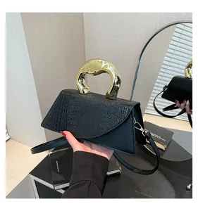 Detail of black crocodile texture handbag featuring an irregular gold metal handle