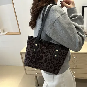 Detail of leopard print tote bag featuring black leather handles and gold rivet accents