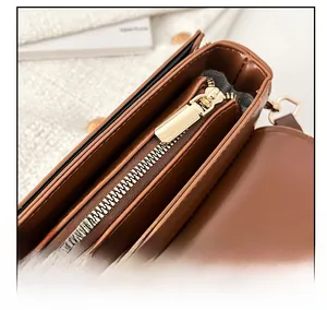 Detailed close-up of smooth gold metal zipper and brown leather texture on handbag