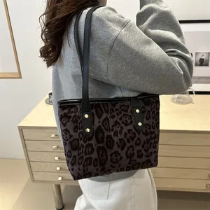 Fashionable leopard print tote bag with black leather straps and golden rivet details