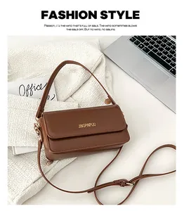 Detail of a brown faux leather crossbody bag with metal logo on a stylish office desk