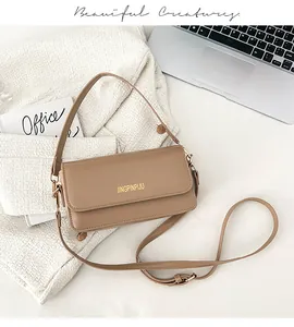 Detail of the golden logo and smooth leather texture on a khaki square crossbody bag