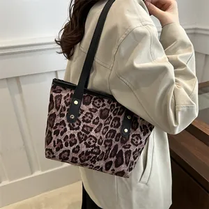Detailed close-up of leopard print tote bag with black straps and gold rivets