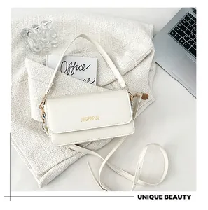 Detail of white PU leather flap bag with gold metal buckle on a woven fabric