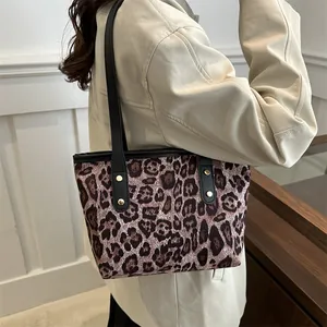 Detail view of leopard print tote bag featuring black shoulder straps and gold rivets