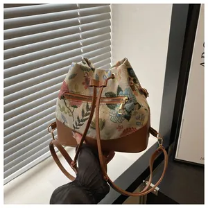 Detailed shot of floral jacquard bucket bag with brown leather trim and gold hardware