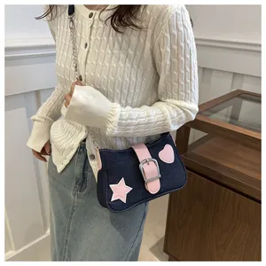 Dettaglio borsa a spalla in denim blu con stelle rosa e tracolla a catena argento