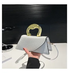 Close-up of white croc-embossed handbag featuring a unique fluid gold metal handle