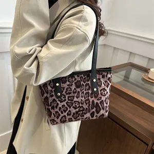 Detail view of leopard print tote bag with black leather straps and gold metal studs