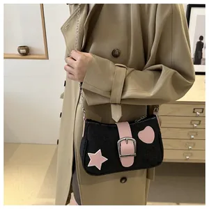 Dettaglio della borsa a spalla in ecopelle nera con toppe rosa a stella e cuore con catena