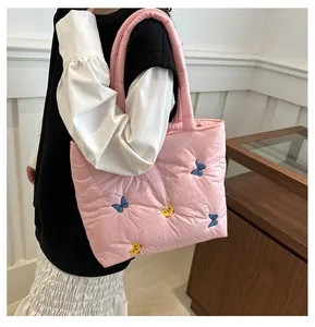 Détail d'un sac cabas matelassé rose avec broderies de papillons bleus et jaunes