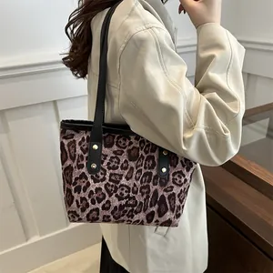 Detail of leopard print tote bag with black leather straps and gold metal rivets