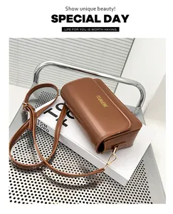 Detail of a brown leather crossbody bag with adjustable strap and gold metal hooks