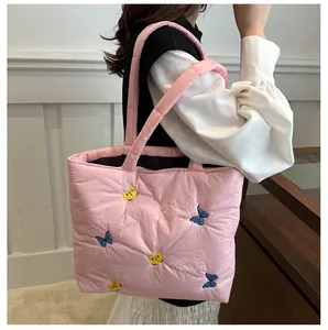 Détail du sac fourre-tout matelassé rose avec broderies de papillons bleus et jaunes