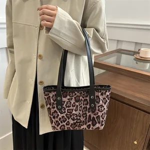 Close-up of leopard print tote bag with leather straps and gold rivet detailing