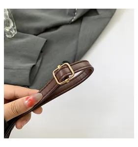 Detail of dark brown crocodile pattern strap with polished gold-tone metal square buckle