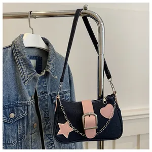 Dettaglio della borsa a spalla in denim con patch a cuore rosa e ciondolo a stella