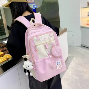 Rear view of pink and white backpack with plush charms on a model in a casual setting