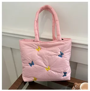 Détail d'un cabas rose matelassé avec broderies papillons colorées et poignées souples