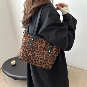Detailed close-up of leopard print tote bag with black leather strap and gold rivets